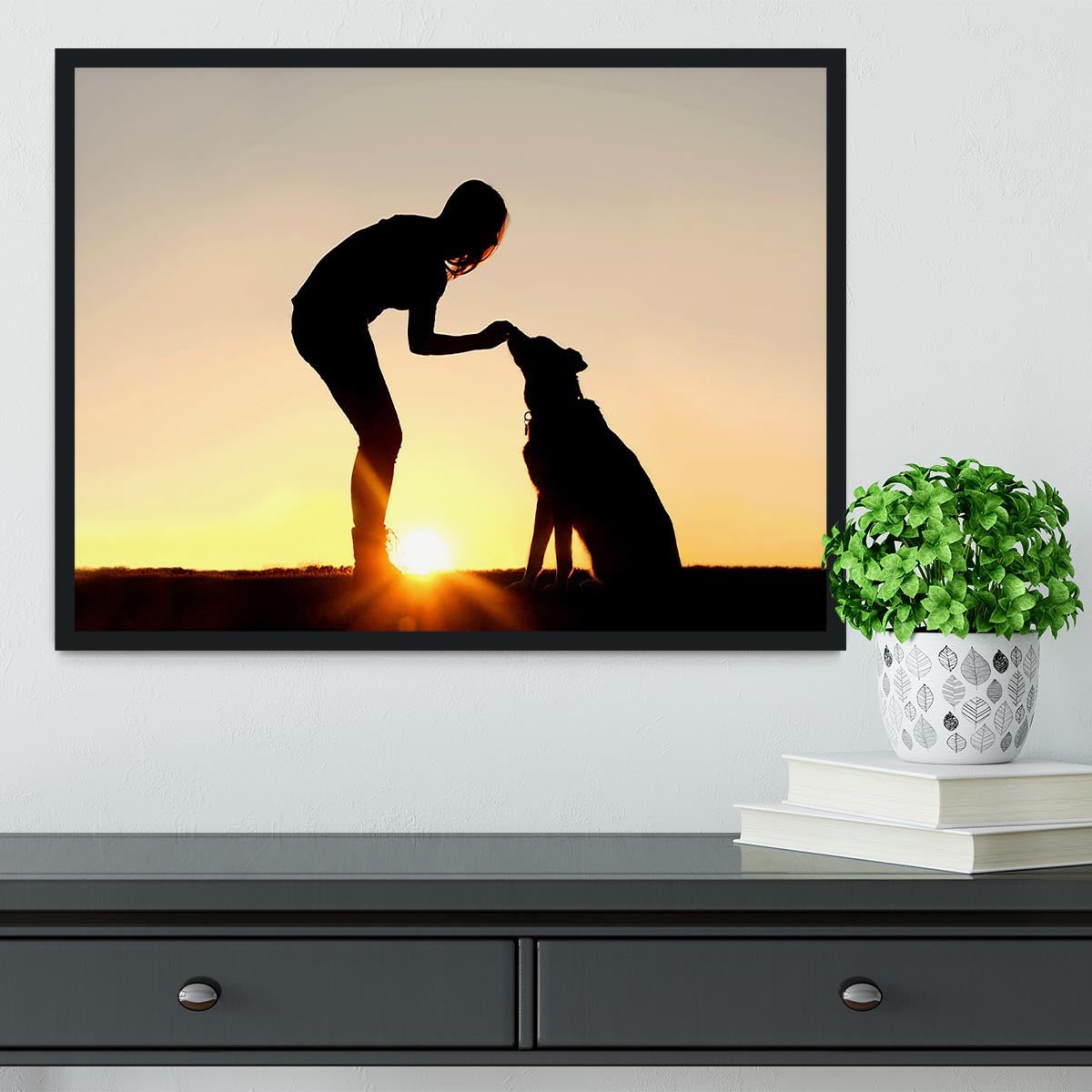 A silhouette of a girl sitting outside in the grass with her pet German Shepherd Mix Dog feeding him treats during training in front of a sunsetting sky. Framed Print - Canvas Art Rocks - 2
