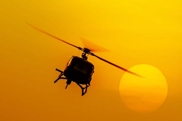 Patrol helicopter flying in sunset Wall Mural Wallpaper